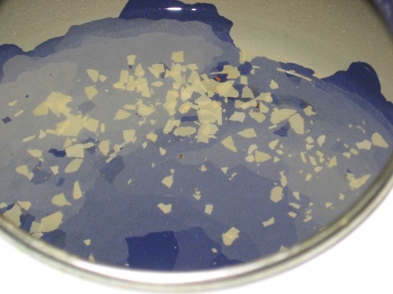 Close-up of white limescale flakes left in the bottom of a metal cooking pot after boiling hard water